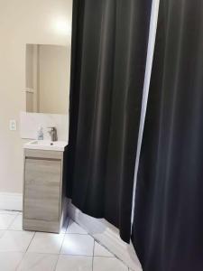 a bathroom with a black shower curtain and a sink at Toronto Travellers Home in Toronto