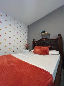 a bedroom with a large bed with white sheets and orange pillows at Green Suíte Comfort in Garanhuns