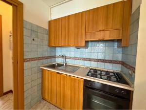 a kitchen with wooden cabinets and a sink and a stove at Magnolia in Grado +3 photos