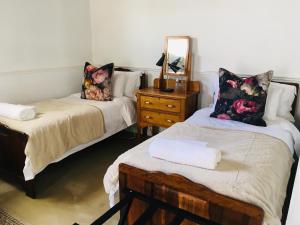 a room with two beds and a dresser with a mirror at Klaarstroom Hotel in Klaarstroom