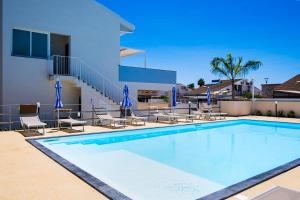 a swimming pool with chairs and a building at Residence Casuzze in Marina di Ragusa