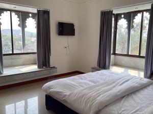 a bedroom with a bed with windows and a flat screen tv at Lotus hotel in Nāthdwāra