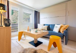 a living room with a blue couch and a table at Superbe Studio Morgins au Pied des Pistes avec Piscine in Morgins
