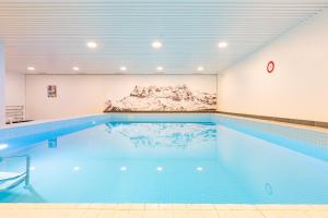 a swimming pool in a building with a painting on the wall at Superbe Studio Morgins au Pied des Pistes avec Piscine in Morgins