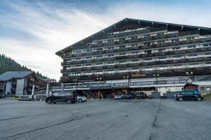 a large building with cars parked in a parking lot at Superbe Studio Morgins au Pied des Pistes avec Piscine in Morgins