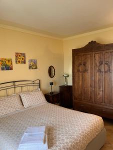 a bedroom with a bed and a wooden cabinet at An tij slè - Nel cuore del borgo in Guarene