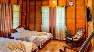 a bedroom with two beds and a chair and a clock at Kaba Saradiel Cabin in Mawanella