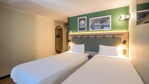 two beds sitting next to each other in a room at Campanile NATURE - Martigues in Martigues +25 photos
