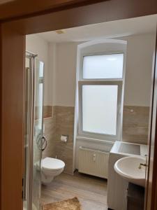 a bathroom with a toilet and a sink and a window at Ferienwohnung Florion 4 in Bernburg +5 photos