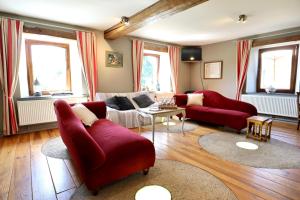 a living room with red couches and a table at Moulin de Meeffe in Wasseiges