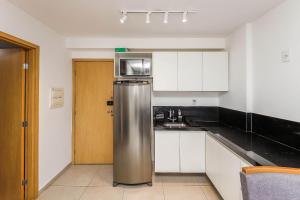 a kitchen with a stainless steel refrigerator and white cabinets at Studio Amalfi piscina academia coz completa in Juiz de Fora