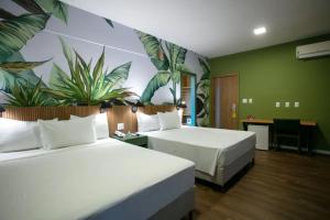 two beds in a hotel room with plants on the wall at Tauá Hotel & Convention Caeté in Roças Novas +50 photos