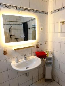 a white bathroom with a sink and a mirror at FeWO Koeppe in Kopp +13 photos