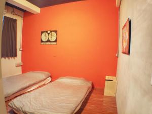 two beds in a room with an orange wall at Knock Knock Hostel in Kaohsiung