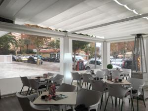 a restaurant with white tables and chairs and windows at Apartamentos Amalia By Mc in Benidorm