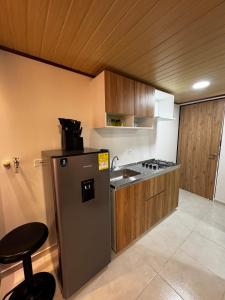 a kitchen with a refrigerator and a sink and a stool at Céntrico apto 202 in Tunja