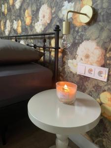 a candle on a white table next to a bed at 't Meuleveld in Harskamp