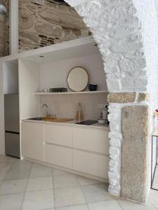 a kitchen with white cabinets and a stone wall at Ancient Wall House in Kampos Paros