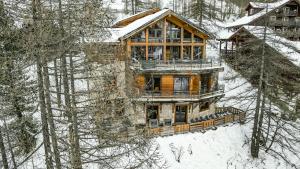 a wooden house in the snow with trees at Chalet Caribou in Isola