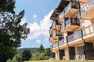 a building with tables and chairs in front of it at Résidence Pierre & Vacances Le Pédrou in Font-Romeu