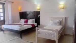 a bedroom with two beds and two lights on the wall at Palm breeze seafront shanzu in Shanzu +15 photos