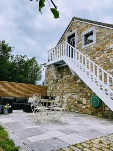 a stone house with a staircase and two chairs at Studio à la campagne in Jalhay