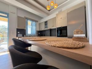 a kitchen with a long counter with chairs at Aristeidis villas in Foiníkion