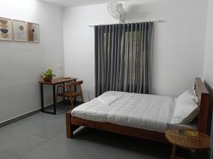 a bedroom with a bed and a table and a window at Times Villa in Anachal