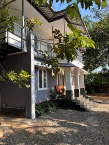 a white house with a porch and stairs at Times Villa in Anachal