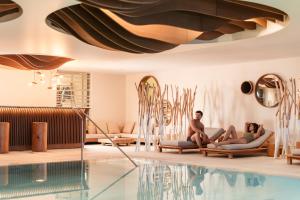 two people sitting on lounge chairs next to a swimming pool at Six Senses Residences & Spa Courchevel in Courchevel