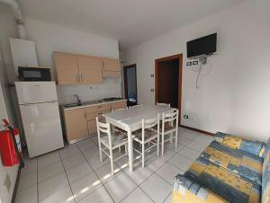 a kitchen with a white table and a white refrigerator at Cozy flat near the centre of Rosolina Mare in Rosolina Mare +22 photos