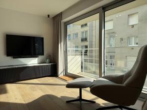 a living room with a chair and a large window at Casiola - Design apartment with sea views in Knokke-Heist