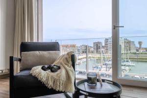 a living room with a chair and a table and a window at 2-slaapkamer appartement met zicht op de Haven in Blankenberge