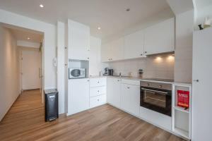 a white kitchen with white cabinets and a wooden floor at 2-slaapkamer appartement met zicht op de Haven in Blankenberge