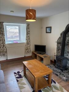 a living room with a table and a fireplace at Braehouse cottage in Kilmory