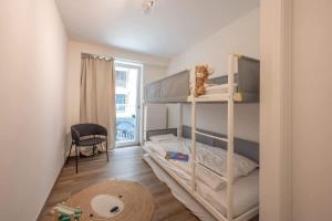 a small bedroom with a bunk bed and a chair at 2-slaapkamer appartement met zicht op de Haven in Blankenberge