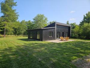 a black house in the middle of a field at Gîtes Prestige LETENDART in Saint-Quentin-en-Tourmont