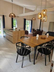 a dining room and living room with a wooden table and chairs at Gîtes Prestige LETENDART in Saint-Quentin-en-Tourmont