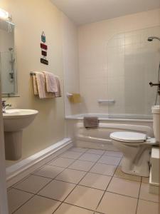 a bathroom with a tub and a toilet and a sink at Courthouse View Penthouse 1 in Clifden +3 photos