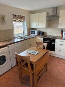 a kitchen with a wooden table with chairs and a sink at Braehouse cottage in Kilmory