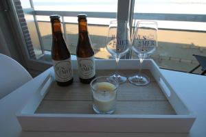 three bottles and two glasses of wine in a cooler at Casiola - Beach Studio with Balcony & Sea View in Zeebrugge
