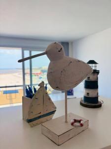 a wooden bird statue on a table with a lighthouse at Casiola - Beach Studio with Balcony & Sea View in Zeebrugge