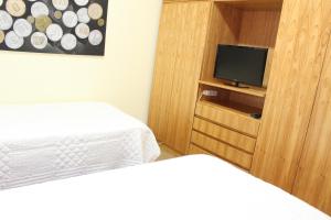 a bedroom with two beds and a tv on a wooden cabinet at OKE Apart Hotel in San Lorenzo