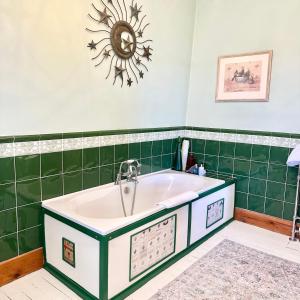 a bath tub in a bathroom with green tiles at Badgers Inn in Petworth +15 photos