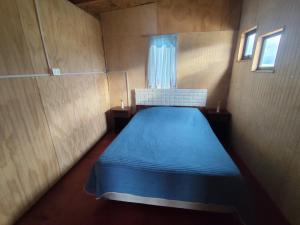 a small bedroom with a blue bed in it at Cabaña Mymemprende in Río Bueno