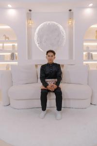 a man sitting on a couch in a room at Amal faiq in Masjid Tanah