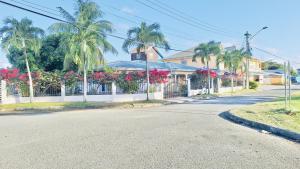 a street with palm trees and a house with flowers at TheWinterHouse in Crown Point