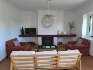 ein Wohnzimmer mit zwei Sesseln und einem Kamin in der Unterkunft Herdade do Gamito in Crato
