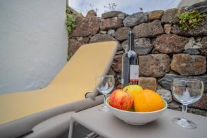 a bowl of fruit on a table with two wine glasses at Villa Alegra Paul do Mar in Paul do Mar