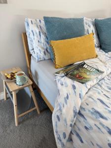 a bed with a table with a book and a cup on it at The Burrow Devon in Longdown